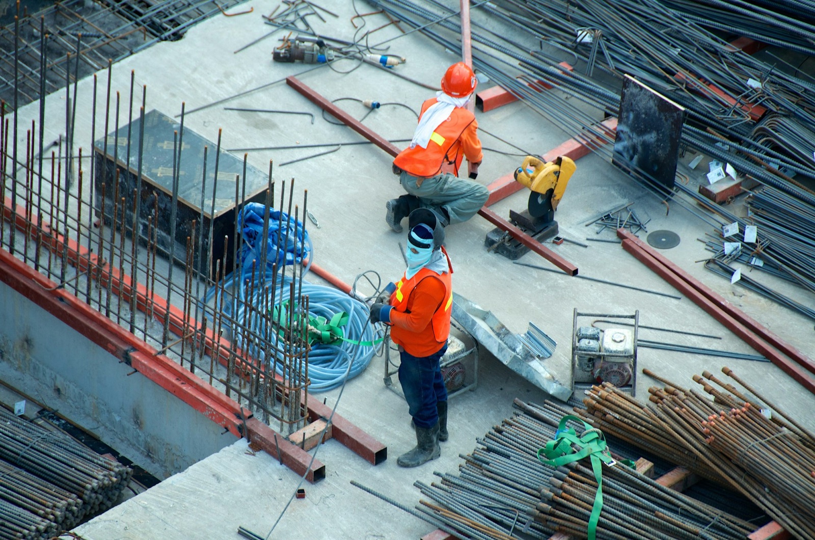 Overhead view of a construction staging floor with rebar, tools, and crew — representative of construction freight